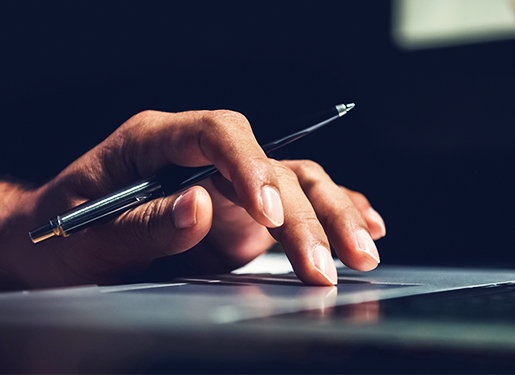 Main tenant un stylo et tapant sur un clavier