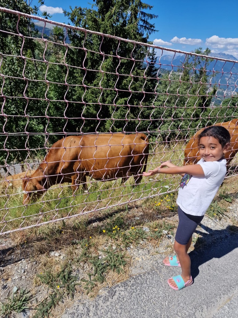 Petite fille montrant une vache dans un pré