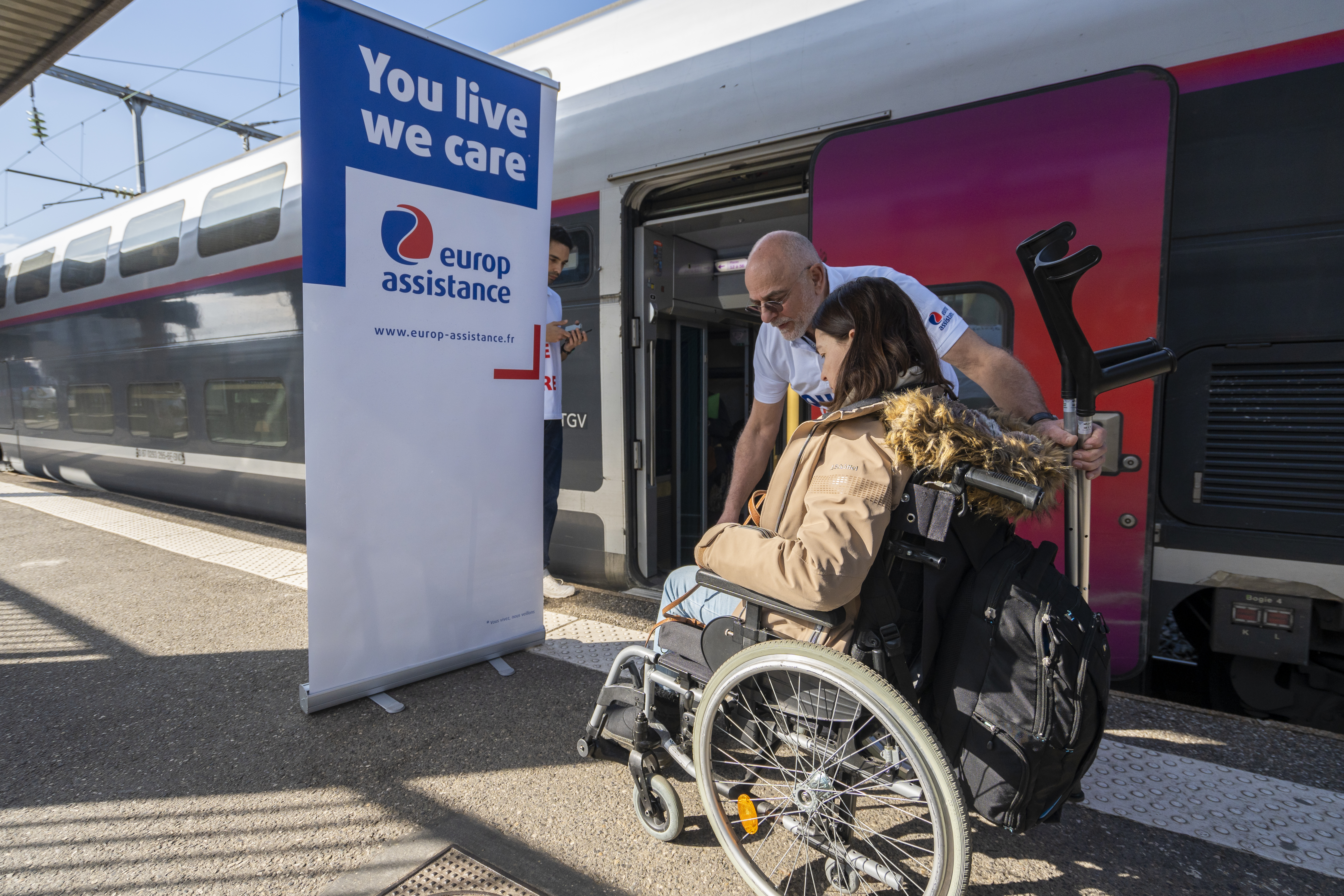 Femme en fauteuil et infirmier devant le Train des neiges Europ Assistance