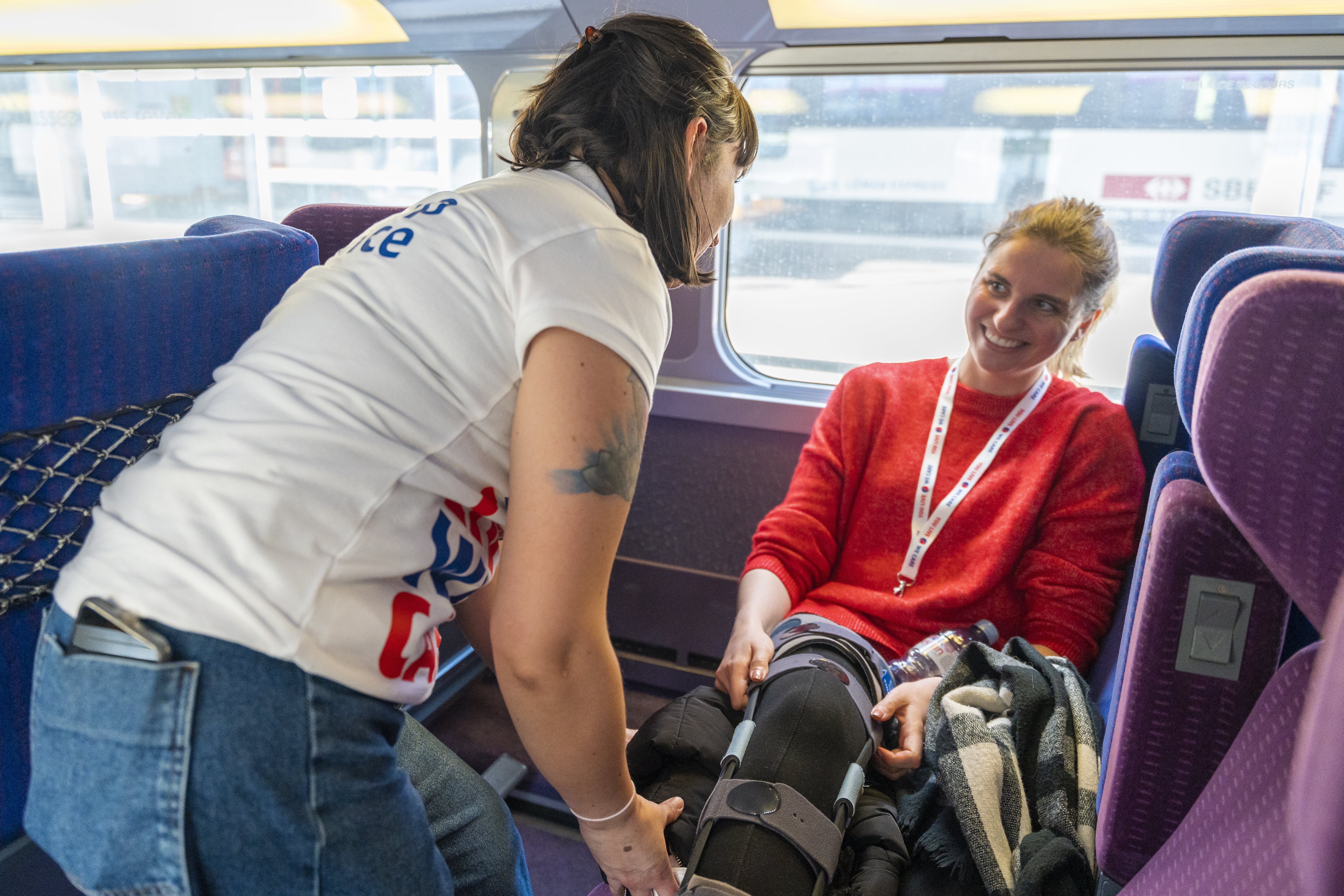 Chargée d'assistance aidant une cliente à s'installer dans le train des neiges